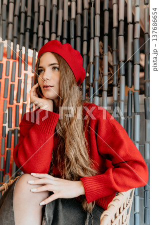 Woman Beret Fashion Young woman in a red beret and sweater sits pensively against a decorative beaded curtain background Woman Beret Fashion Young woman in a red beret and sweater sits pensively against a decorative beaded curtain background 137686654