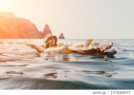 Woman, Inflatable Raft, Sea: Relaxing on a Raft in the Ocean on a Sunny Day. Woman, Inflatable Raft, Sea: Relaxing on a Raft in the Ocean on a Sunny Day. 137686655