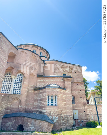 Historic Byzantine church exterior with distinctive architecture, featuring stone walls and arched windows under a clear blue sky 137687328