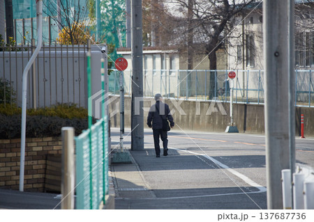 冬の朝の都市の住宅街で歩く一人のシニア男性の姿 冬の朝の都市の住宅街で歩く一人のシニア男性の姿 137687736