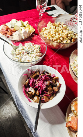 Colorful assortment of traditional dishes served on a festive table with red tablecloth, featuring salads, fruits, and pickled vegetables in various bowls Colorful assortment of traditional dishes served on a festive table with red tablecloth, featuring salads, fruits, and pickled vegetables in various bowls 137688044