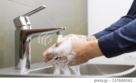 手洗いする男性の手元。石鹸の泡がついている。水道から水が流れている。 手洗いする男性の手元。石鹸の泡がついている。水道から水が流れている。 137689162
