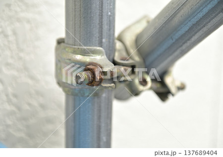 錆びたボルトで固定された工事現場の足場用金属クランプ（自在クランプ） 137689404