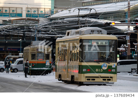 雪景色の横川駅前に並ぶ広島電鉄の電車 137689434
