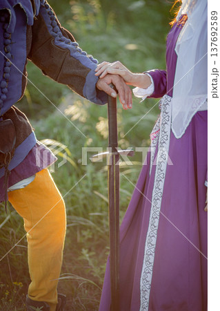 A female hand rests on a male sword hilt. Vertical photo. 137692589