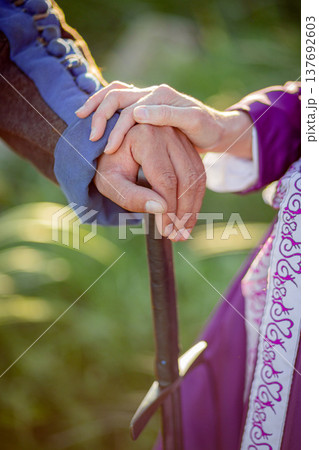 A female hand rests on a male sword hilt. A vertical close-up photo A female hand rests on a male sword hilt. A vertical close-up photo 137692603