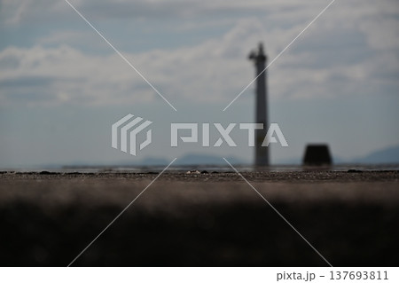 海に佇む防波堤と遠くの灯台の情緒的な風景 137693811