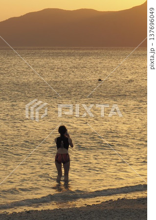 夕日と海で遊ぶビキニの女性　沖縄の風景 137696049