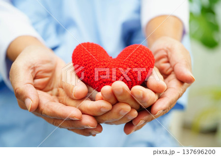 Asian elder senior woman patient holding red heart in hospital. Asian elder senior woman patient holding red heart in hospital. 137696200