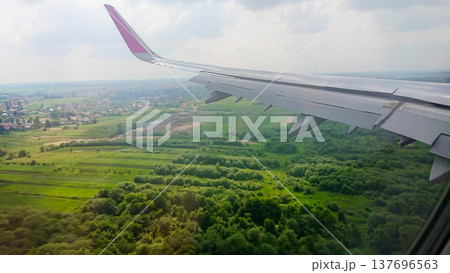 Airplane wing extends over lush green fields Airplane wing extends over lush green fields 137696563