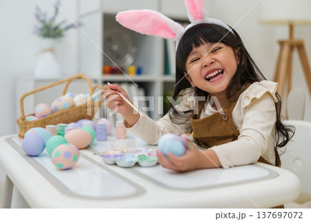 happy preschool child girl wearing bunny ears painting and decorating colorful egg at home on easter day happy preschool child girl wearing bunny ears painting and decorating colorful egg at home on easter day 137697072