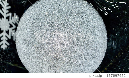 sparkling silver christmas bauble glistens with glitter beside crystal snowflake on dark pine branch evoking winter magic perfect for festive wallpaper or holiday card backdrop sparkling silver christmas bauble glistens with glitter beside crystal snowflake on dark pine branch evoking winter magic perfect for festive wallpaper or holiday card backdrop 137697452