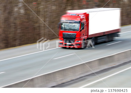 Red semi truck transporting goods on highway asphalt Red semi truck transporting goods on highway asphalt 137698425