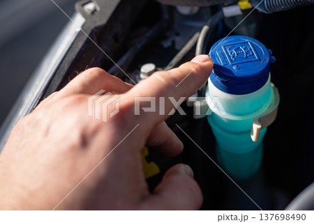 Hand opening blue cap of windshield washer reservoir Hand opening blue cap of windshield washer reservoir 137698490