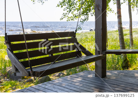 A wooden porch swing hangs on a seaside deck A wooden porch swing hangs on a seaside deck 137699125