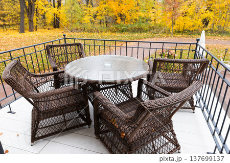 Wicker patio table and chairs arranged on a balcony 137699137
