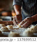 hands shaping dumplings on a floured surface, soft natural light, shallow focus, authentic cooking process, 137699512