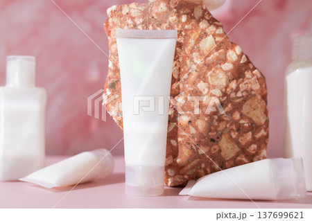 Minimal cosmetic skincare lotion tubes with natural stone on pink background, beauty product packaging mockup 137699621
