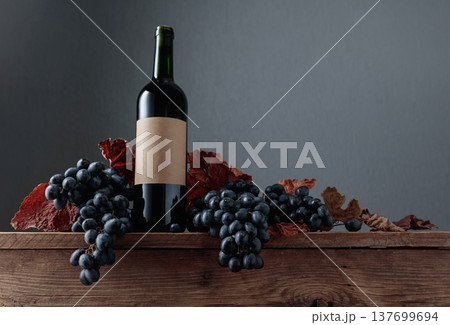 Red wine bottle with blue grapes on an old wooden table. Red wine bottle with blue grapes on an old wooden table. 137699694