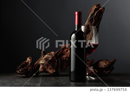 Red wine and old weathered snag on a black stone table. 137699758