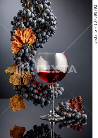 Red wine with blue grapes on a black reflective background. 137699792
