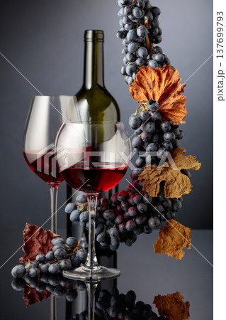 Glasses and bottle of red wine with blue grapes. 137699793