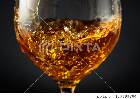 White wine of rich amber color being poured into a glass. 137699804