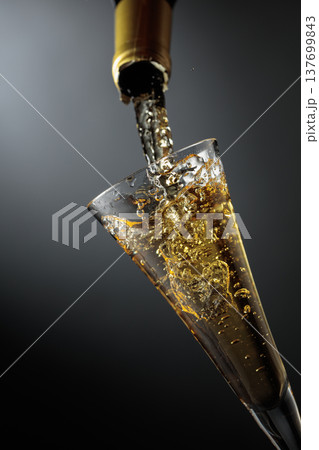 White sparkling wine is poured from a bottle into a glass. White sparkling wine is poured from a bottle into a glass. 137699843