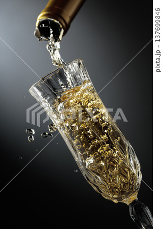 White sparkling wine is poured from a bottle into a glass. 137699846