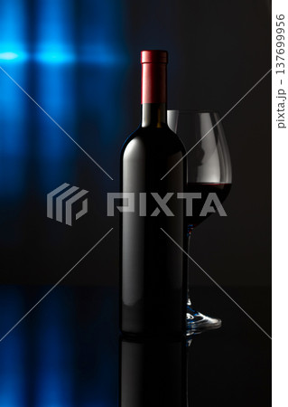 Glass and bottle of red wine on a black reflective background. 137699956