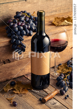 Bottle of red wine and blue grapes on a old wooden table. 137699957