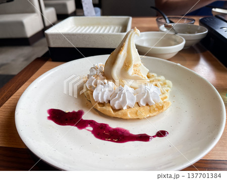 ソフトクリームとホイップクリームをトッピングしたワッフルケーキ。ベリーソースを添えて。 ソフトクリームとホイップクリームをトッピングしたワッフルケーキ。ベリーソースを添えて。 137701384