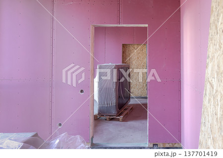 Interior construction with pink drywall walls and doorway in new building 137701419