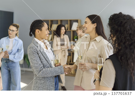 Business women networking handshake at office event, colleagues greeting warmly 137701637