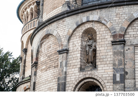 Basilica of St. Apostles in Cologne, Germany. The structure features two prominent towers and intricate architectural details against a cloudy sky. Basilica of St. Apostles in Cologne, Germany. The structure features two prominent towers and intricate architectural details against a cloudy sky. 137703500
