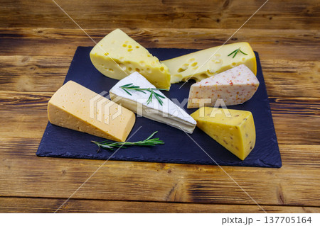 Set of various types of cheese on black slate board on a wooden table 137705164