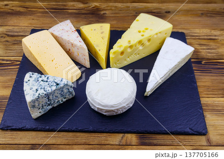 Set of various types of cheese on black slate board on a wooden table 137705166