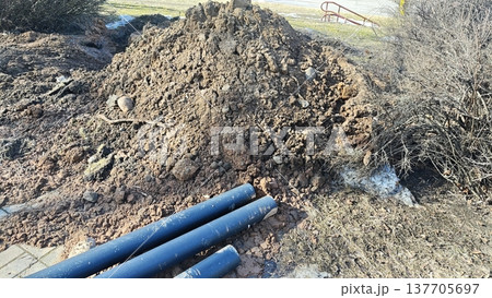 Excavation site with plastic utility pipes and soil pile for underground pipeline installation Excavation site with plastic utility pipes and soil pile for underground pipeline installation 137705697