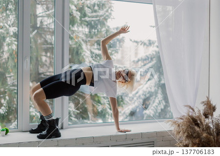 Beautiful woman posing on a large window in a Beautiful woman posing on a large window in a 137706183