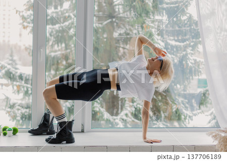 Beautiful woman posing on a large window in a Beautiful woman posing on a large window in a 137706189