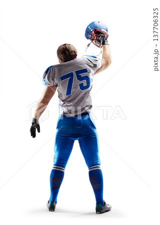Football. NFL. Football player holding the helmet in his hand. Sport emotions. Sport victory. Joy in football. Back view. Isolated 137706325