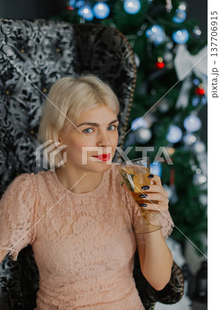 A woman sits on a chair near a Christmas tree with 137706915