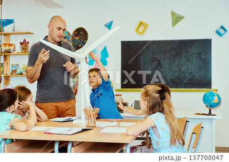 Teacher and students explore a wind turbine model during hands-on science lesson in a classroom 137708047