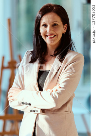 Confident professional woman smiling with arms crossed in modern office environment 137708053