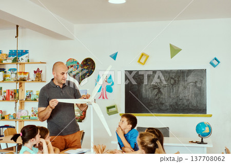 Teacher demonstrating a model wind turbine to elementary students during a hands-on classroom science lesson 137708062