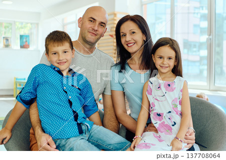 Happy family portrait: parents with son and daughter smiling in a bright living room Happy family portrait: parents with son and daughter smiling in a bright living room 137708064