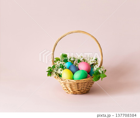 Easter painted eggs in a basket with flowers on pink background. Easter cute greeting card. Space for text. Easter painted eggs in a basket with flowers on pink background. Easter cute greeting card. Space for text. 137708384
