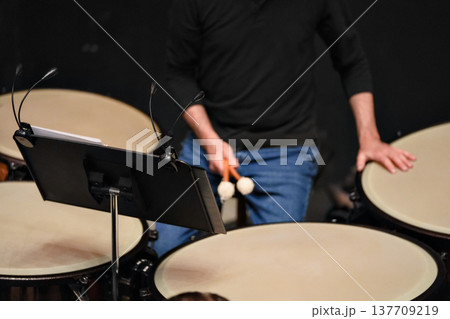 Musician playing timpani during orchestra rehearsal indoors Musician playing timpani during orchestra rehearsal indoors 137709219