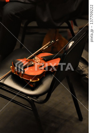 Violin resting on chair in concert hall backstage setting Violin resting on chair in concert hall backstage setting 137709222