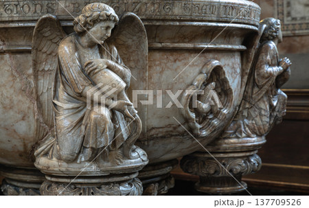 Masterfully carved in marble, this baptismal font from St. Mary Abbots, Kensington, radiates reverence and beauty. It features graceful figures in high relief, such as a kneeling angel holding a 137709526
